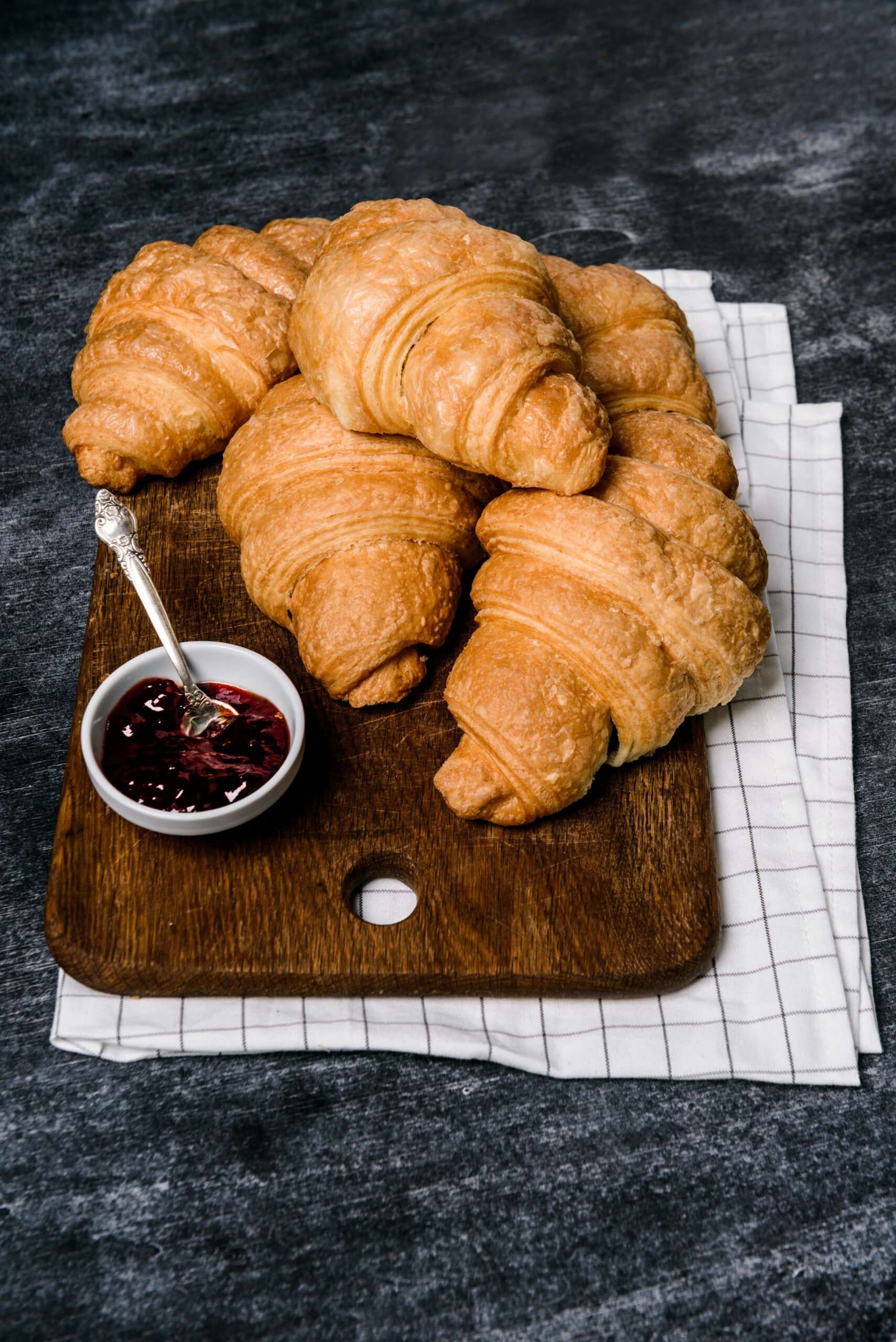 Picture of croissants and pot with jam aside on grey table